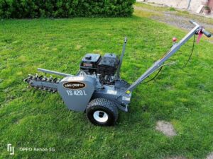 Trancheuse à chaîne LOCATOP31 TS 420 L, grise, avec moteur à essence, posée sur une pelouse verte, prête à l'emploi.
